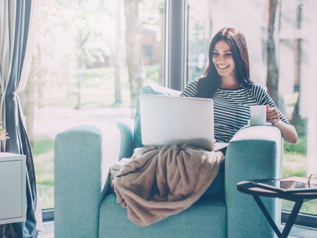 woman staying at home on laptop smiling
